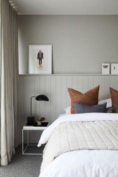 a bed with white sheets and pillows in a bedroom next to a wall mounted painting