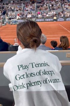 a woman with a towel on her back at a tennis match in front of an audience