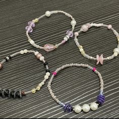 three bracelets with beads and charms on a table