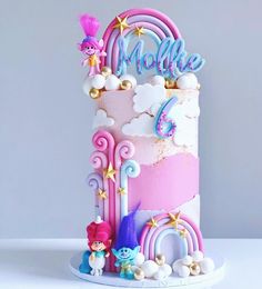 a pink and blue cake with stars, clouds, and rainbows on it's side