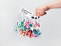 a person's hand holding a clear bag filled with stickers