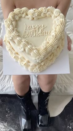 a woman holding a heart shaped birthday cake