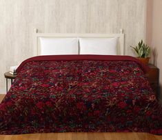 a bed with a red comforter and pillows on top of it in a room