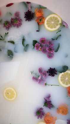 flowers and lemons are floating in a bathtub with soapy water on the floor