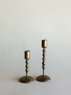 two metal candlesticks sitting next to each other