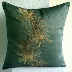 a green pillow sitting on top of a white chair next to a wall with a plant embroidered on it