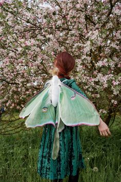 a woman in a green dress with a large butterfly on her back