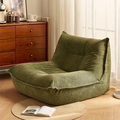 a green bean bag chair sitting on top of a wooden floor next to a window