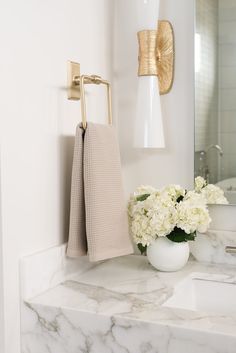 a bathroom with marble counter top and gold towel rack on the wall next to sink