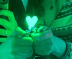 two people are holding up their cell phones with the light shining on them in the shape of a heart