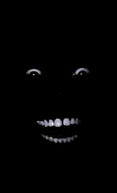 a black and white photo of a person's face with teeth in the dark