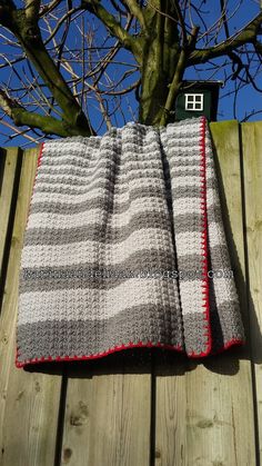 two blankets sitting on top of a wooden fence next to a tree with no leaves