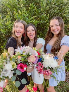 three girls are holding flowers in their hands and posing for the camera with each other