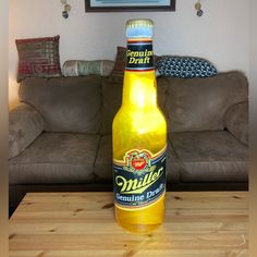 a beer bottle sitting on top of a wooden table next to a brown couch in a living room