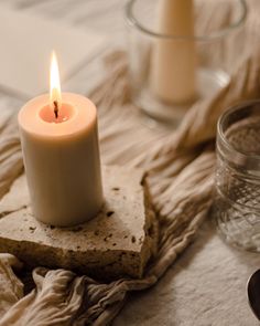 a lit candle sitting on top of a piece of stone