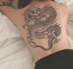 a woman laying on top of a bed with a tattoo on her back and arm