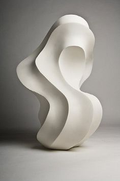 a white sculpture sitting on top of a table next to a gray wall and floor