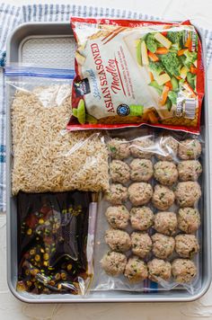 an open lunch box with rice, meatballs and veggies