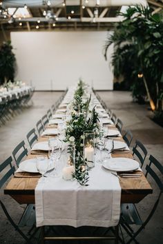 a long table is set with white plates and place settings