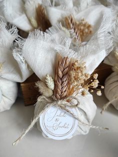 some dried flowers are sitting next to each other on a white table cloth with a tag