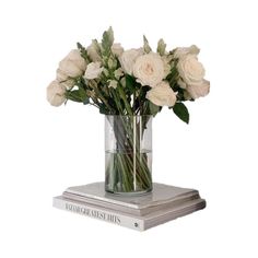 white roses in a clear vase on top of two books