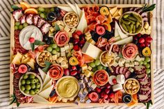 a wooden tray filled with lots of different types of cheese and crackers on top of a striped table cloth