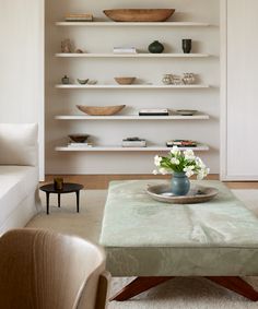 a living room filled with lots of shelves and flowers on top of a coffee table