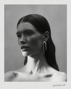 a black and white photo of a woman with long hair wearing large earrings