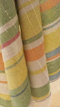 three multicolored striped curtains are hanging on a wooden floor in front of a window