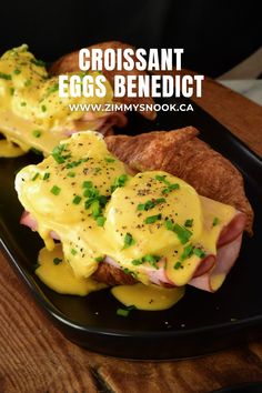 a black plate topped with an egg benedict and croissants on top of it