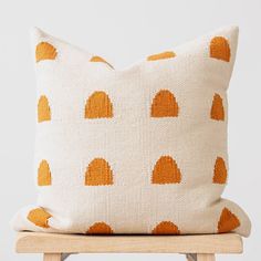 an orange and white pillow sitting on top of a wooden chair