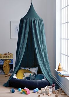 a canopy bed in the middle of a room with toys on the floor around it