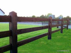 a wooden fence in front of a grassy field