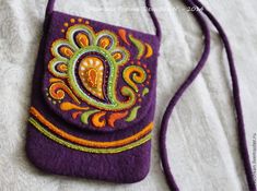 a purple purse with an orange and green paisley design on the front, sitting on a white surface