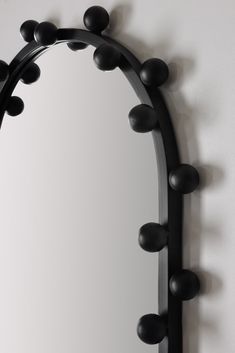 a mirror that is on the wall with some black balls around it's edge