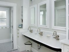 a white bathroom with double sinks and mirrors