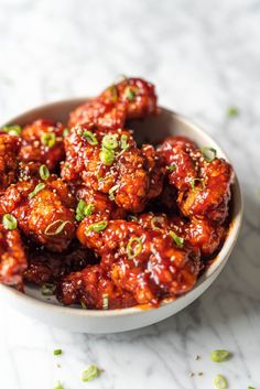 a bowl filled with meatballs covered in sauce and garnished with scallions