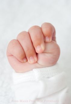 a close up of a baby's hand on top of a white blanket