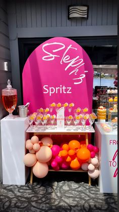 there is a pink sign that says spritz on it and many balloons are in front of it