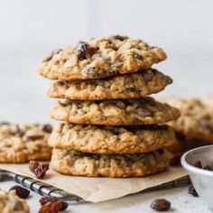 chocolate chip cookies stacked on top of each other with raisins in the background