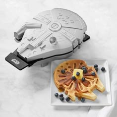 a white plate topped with blueberries and waffles next to a star wars replica