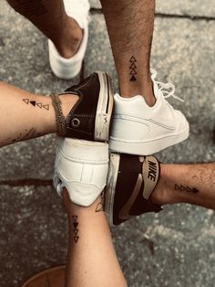 three people with tattoos on their legs standing next to each other and holding hands together