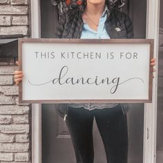 a woman holding up a sign that says, this kitchen is for dancing on the front door