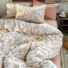 an unmade bed with floral sheets and pillows