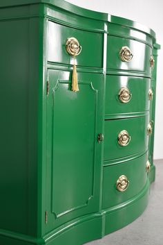 a green dresser with gold handles and knobs on the doors is shown in this image