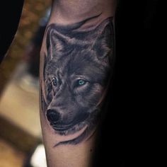 a man's arm with a wolf tattoo on it and blue eyes in the center