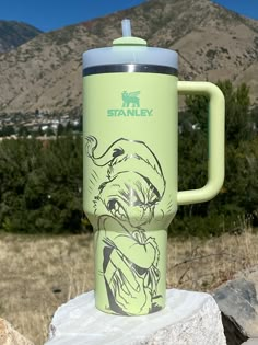 a green travel mug sitting on top of a rock