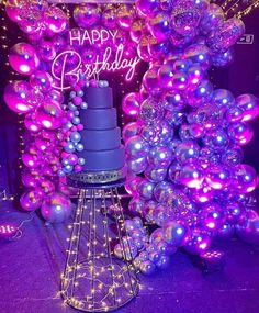 a purple birthday cake surrounded by balloons and streamers with the words happy birthday written on it