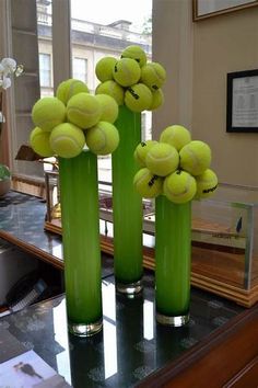 three tall vases with tennis balls in them