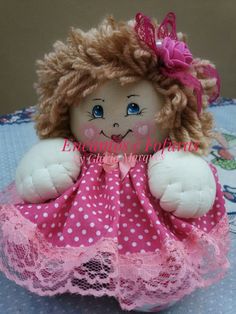 a small doll with blonde hair and blue eyes wearing a pink dress on a table